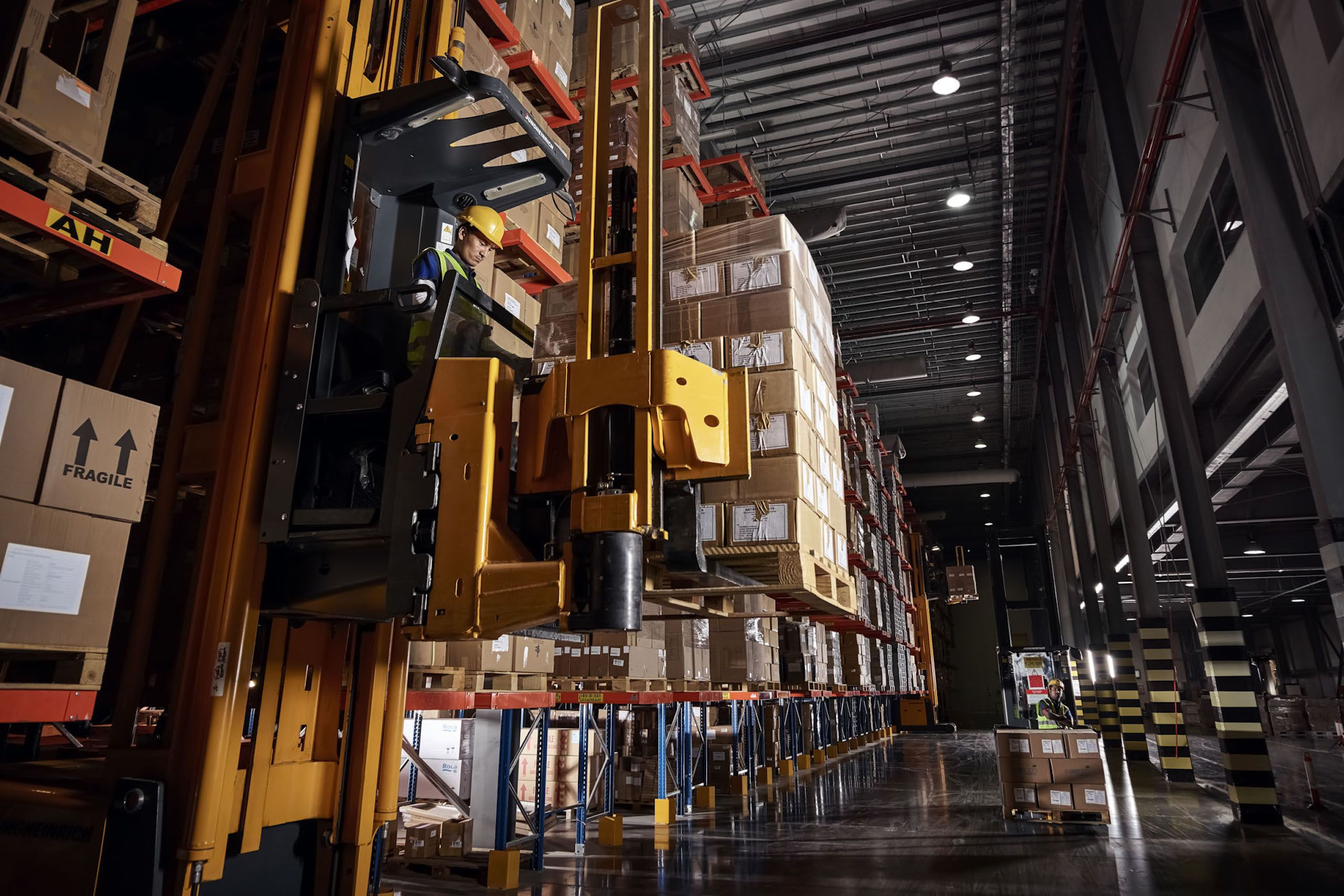 Inside of a warehousing and storage facility, boxes stacked to the ceiling, with equipment to move the boxes