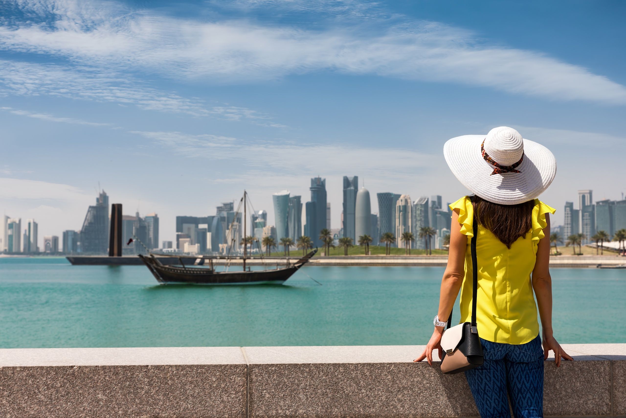 Traveller woman with sunhat enjoys the view to the skyline of Doha, Qatar