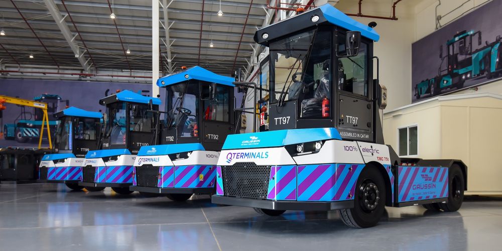 Gaussin logistics equipment, bright blue, white, and black in color, lined up in a row